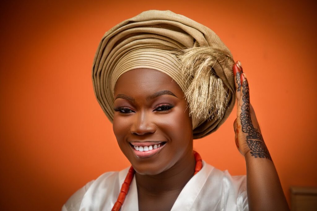 Portrait of a cheerful African woman in vibrant Nigerian gele, showcasing cultural beauty and tradition.