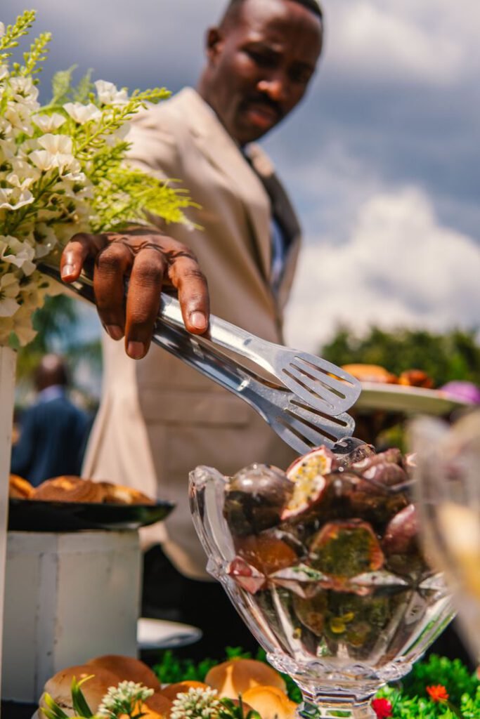 pexels photo 34593744 A man in a suit serves desserts at an elegant outdoor event with floral arrangements.