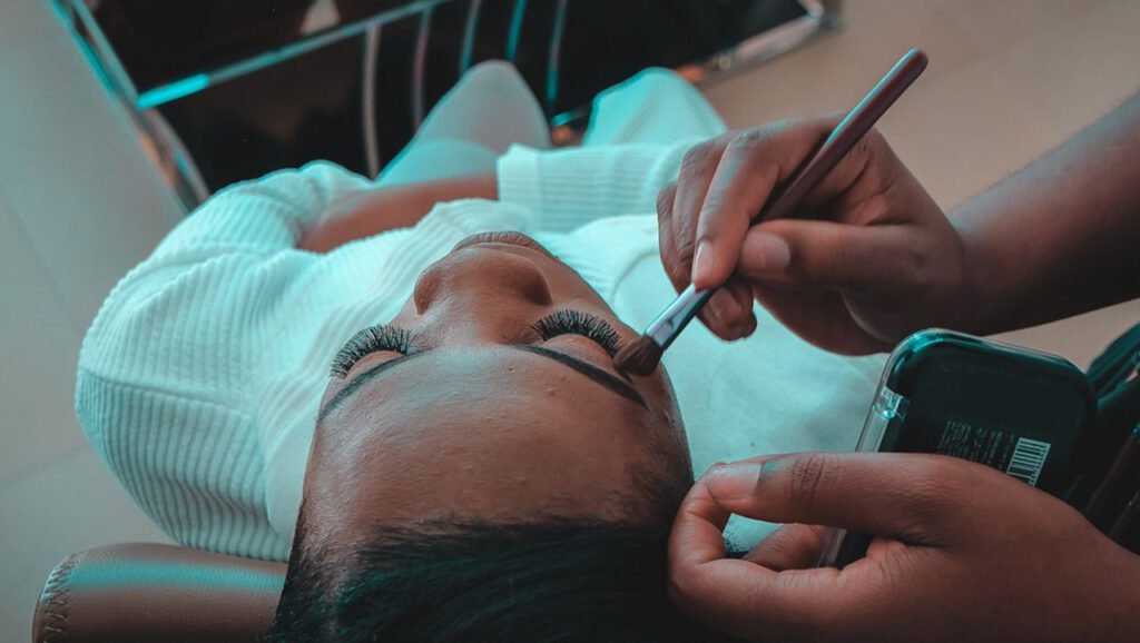 Close-up of a professional makeup artist applying eye makeup in a salon setting.